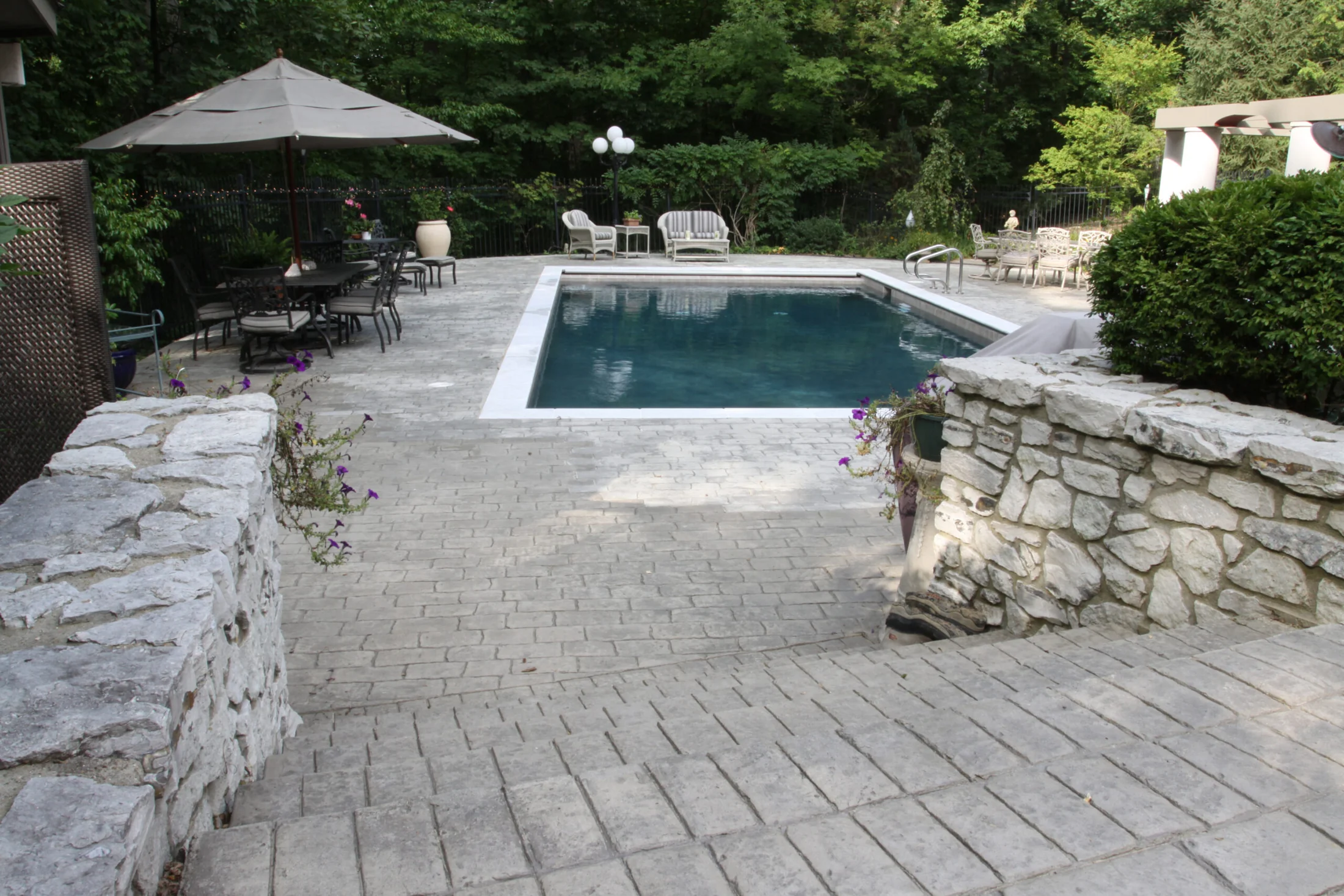 Gunite pool approached through stone walls and a paved garden terrace