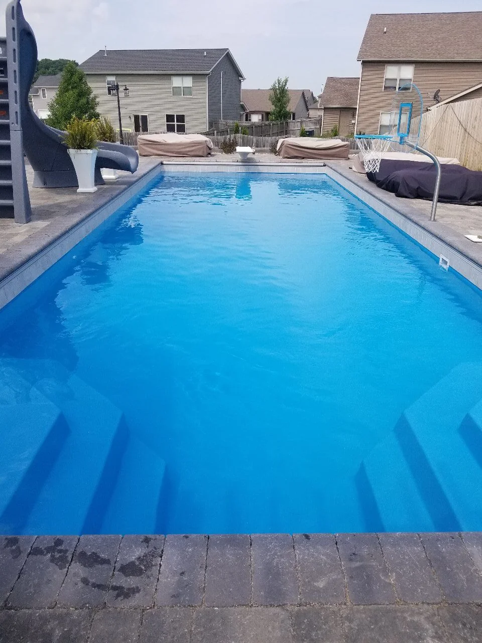 Rectangular fiberglass pool with integrated steps and a paver border